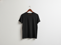 Front view of a plain black minimalist short-sleeve t-shirt on a wooden hanger against a clean white textured wall.
