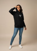 Woman wearing a black Sabio hoodie with a logo and blue jeans