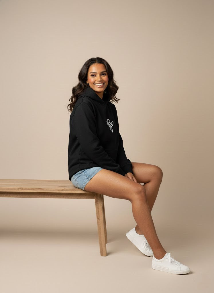 Woman wearing a black Sabio hoodie with a logo and blue jeans