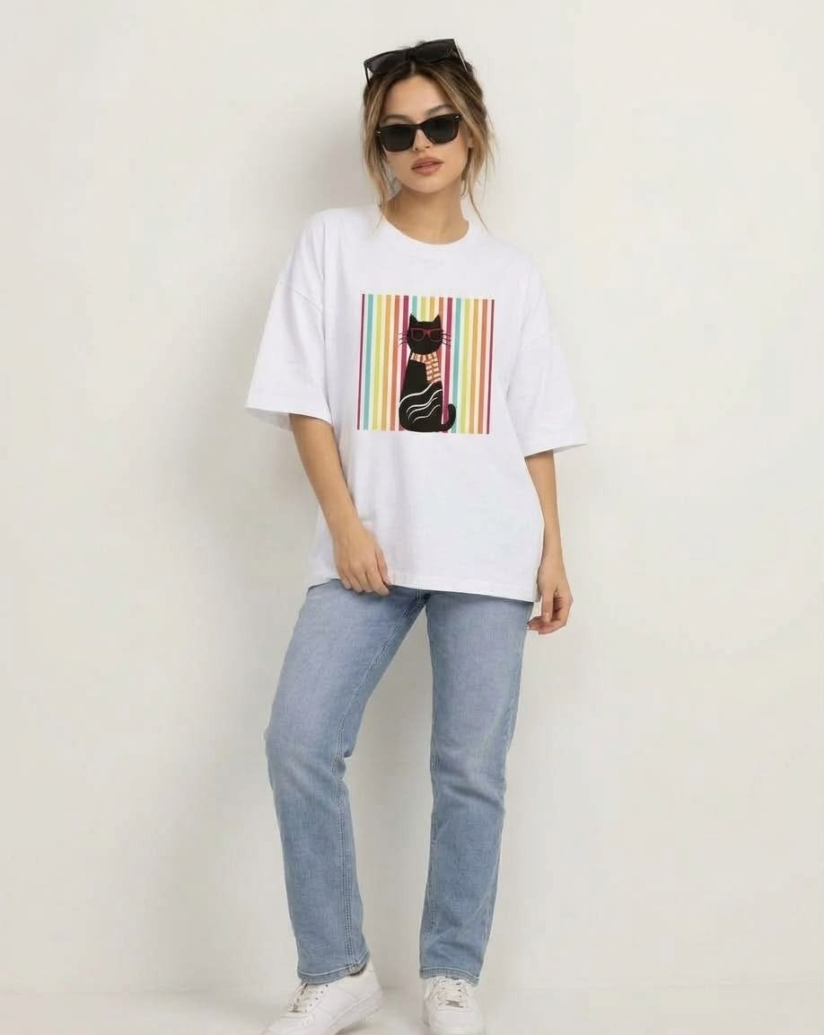 Model wearing oversized white graphic cat tee styled with straight-leg blue jeans and white sneakers.