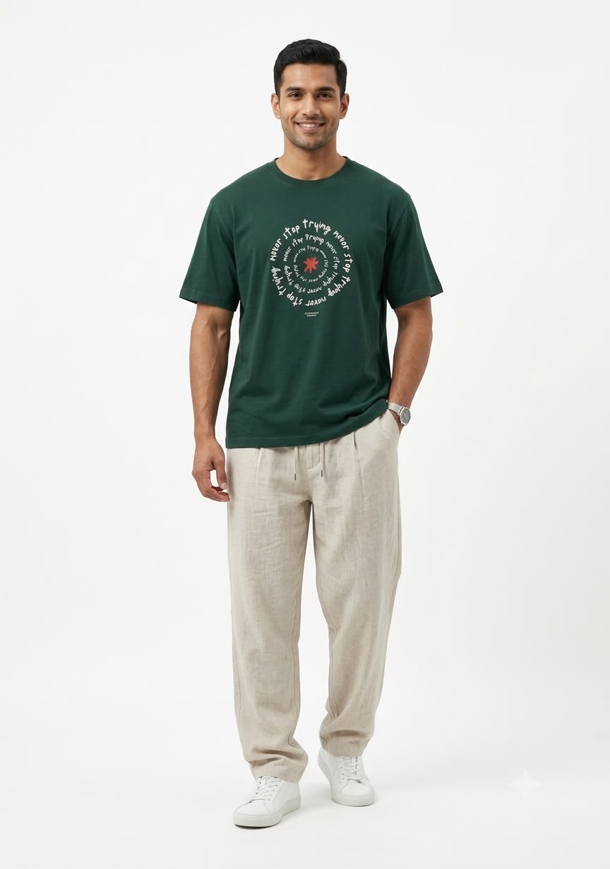 A flat-lay or hanger view of the dark green cotton t-shirt. The chest features a large, central circular graphic with white text repeating "never stop trying" around a red asterisk. A brand label is visible at the neck.