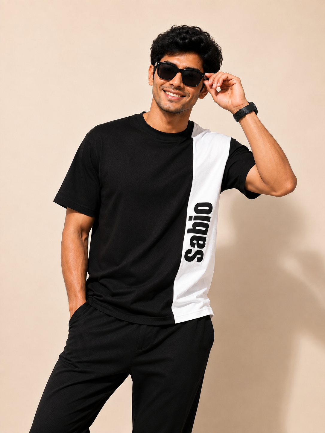A black short-sleeve t-shirt with a bold white vertical stripe on the right side featuring the word 'Sabio' in black text, displayed flat against a light beige background.