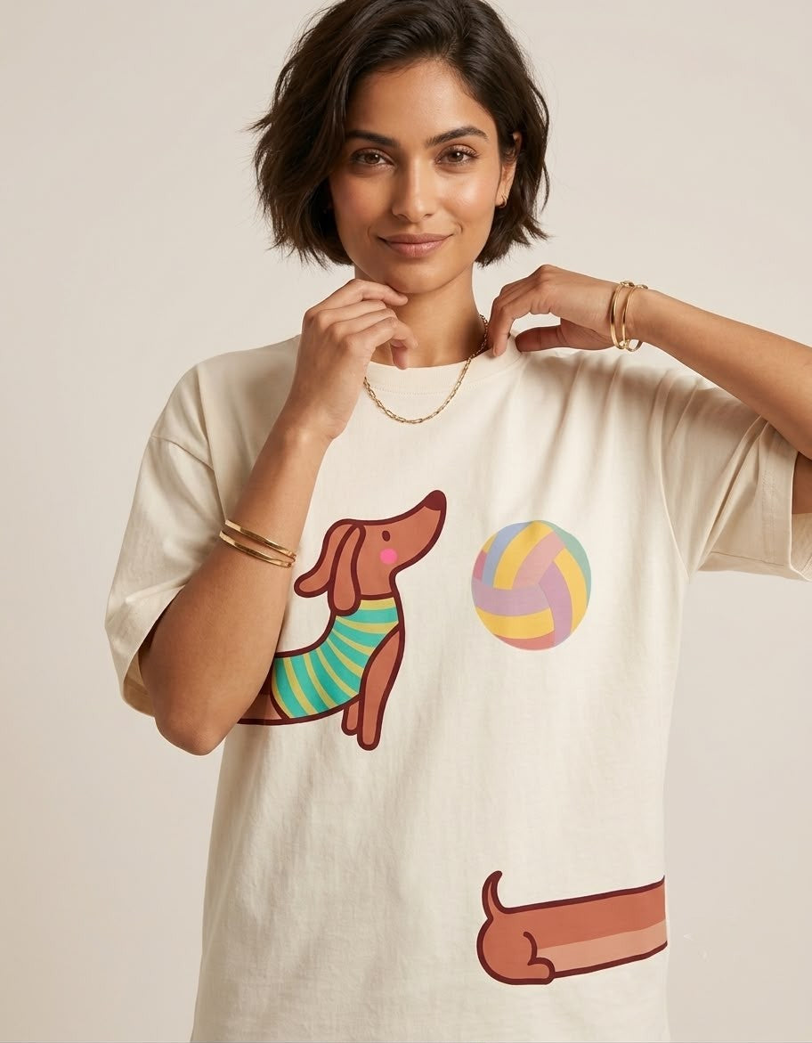 Close-up of The Sabio relaxed fit crew neck t-shirt showing detailed printed graphics of a sweater-wearing dachshund and beach ball.