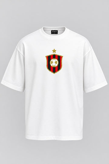 A white short-sleeve crewneck t-shirt featuring a red and black striped shield crest with a gold star and soccer ball on the chest, displayed on a neutral gray background.
