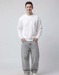 Male model wearing The Sabio solid white relaxed crewneck fleece sweatshirt, front close-up view.