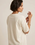Rear angle view of a model wearing The Sabio off-white drop-shoulder oversized cotton t-shirt.
