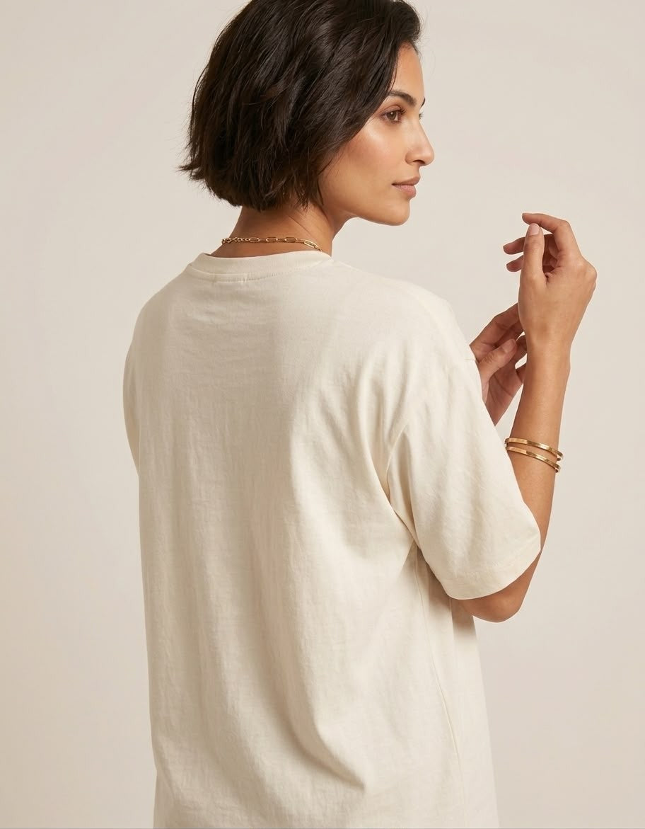 Rear angle view of a model wearing The Sabio off-white drop-shoulder oversized cotton t-shirt.