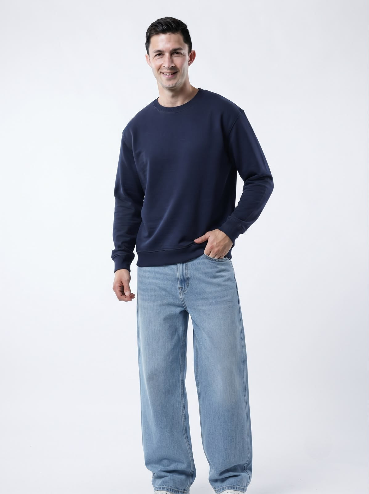 Male model adjusting The Sabio dark navy crewneck fleece sweatshirt styled casually with baggy jeans and white sneakers.