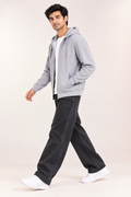 Full-length view of male model wearing The Sabio grey heather fleece zip hoodie with hood up and hands in pockets.