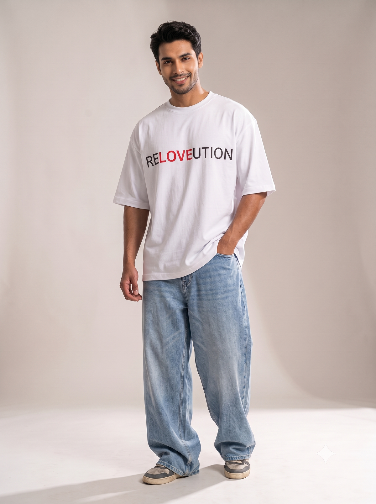 Side profile shot of a male model wearing The Sabio oversized white RELOVEUTION t-shirt and baggy light blue denim jeans in a studio setting, showcasing the loose-fitting drop-shoulder silhouette.
