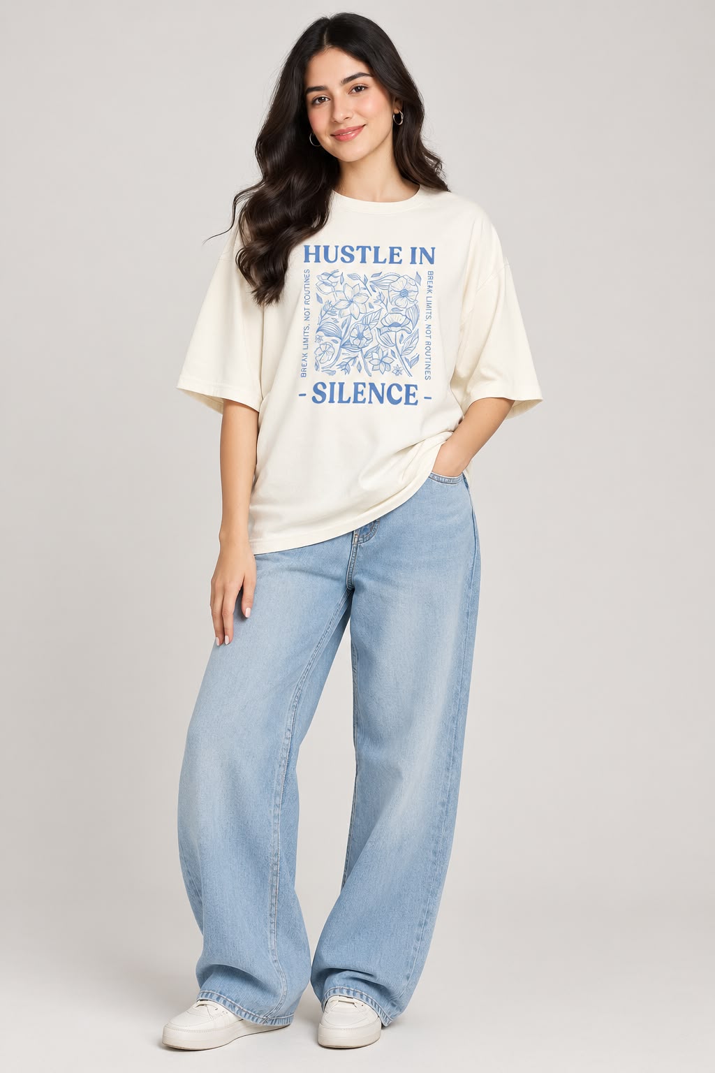 Front product flat view of an off-white oversized crewneck t-shirt featuring a blue floral sketch graphic and "Hustle In Silence" lettering centered on the chest.